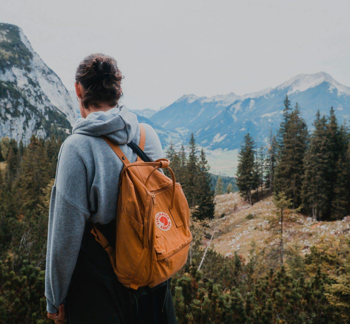 woman wearing backpack near trees during day